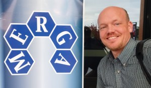 The MERGA logo on a sign outside the building, with Sam Otten next to it smiling toward the camera. He is bald with a subtle dark blond goatee.